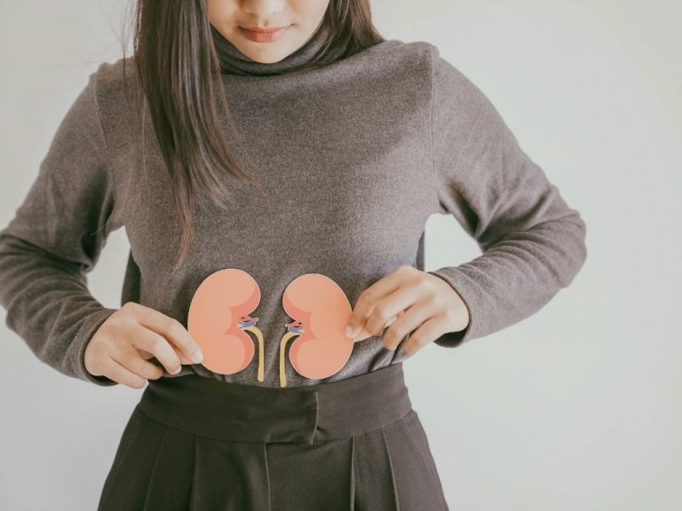 Photo d'une jeune femme montrant l'emplacement des reins dans le corps humain, illustration d'un article portant sur la toxicité du plomb.